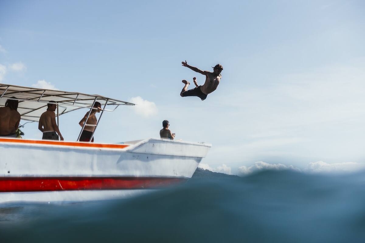 Menschen springen von einem Boot ins Wasser