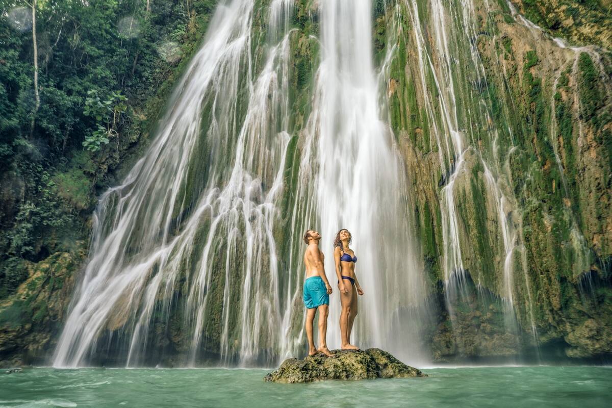 Paar steht auf einem Felsen vor einem Wasserfall
