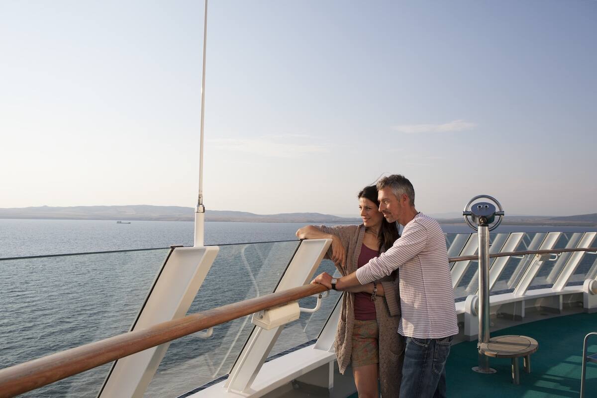 Paar steht an der Reling und genießt die Fahrt