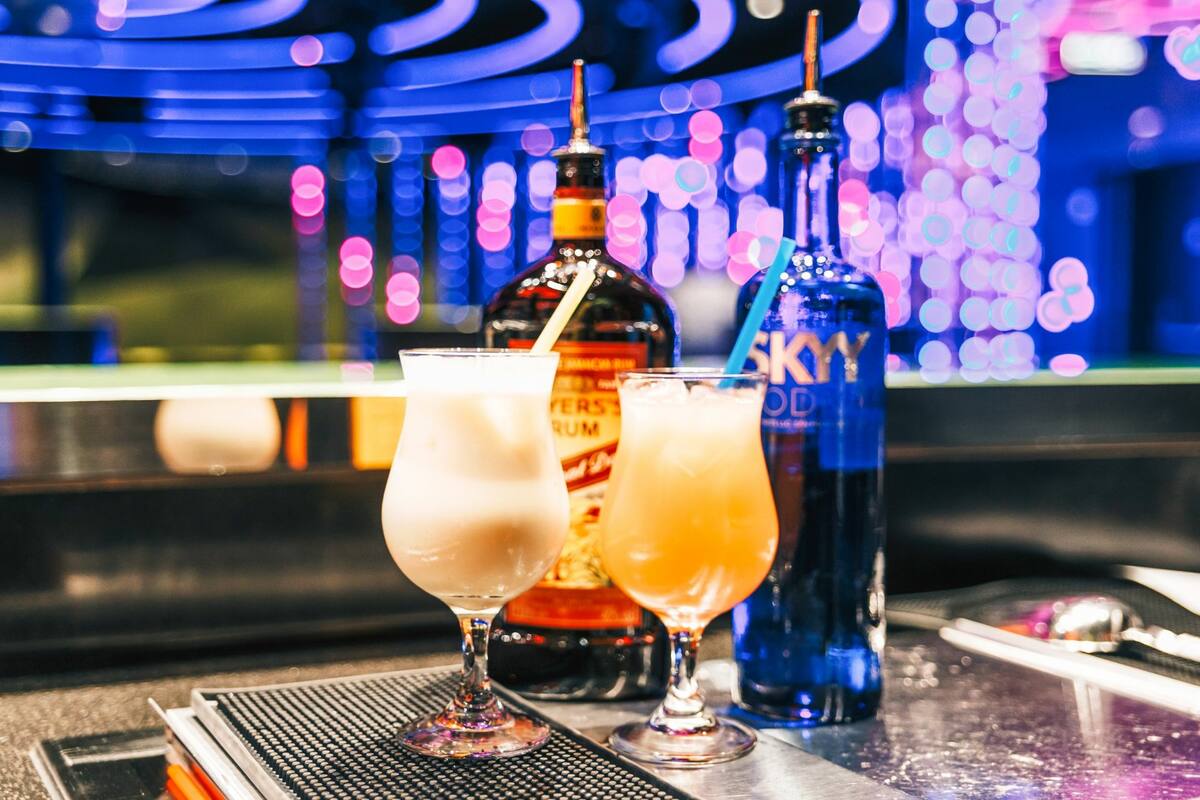 Zwei gemixte Cocktails stehen vor den Flaschen der Hauptzutat - Skyy Vodka und Myers's Rum