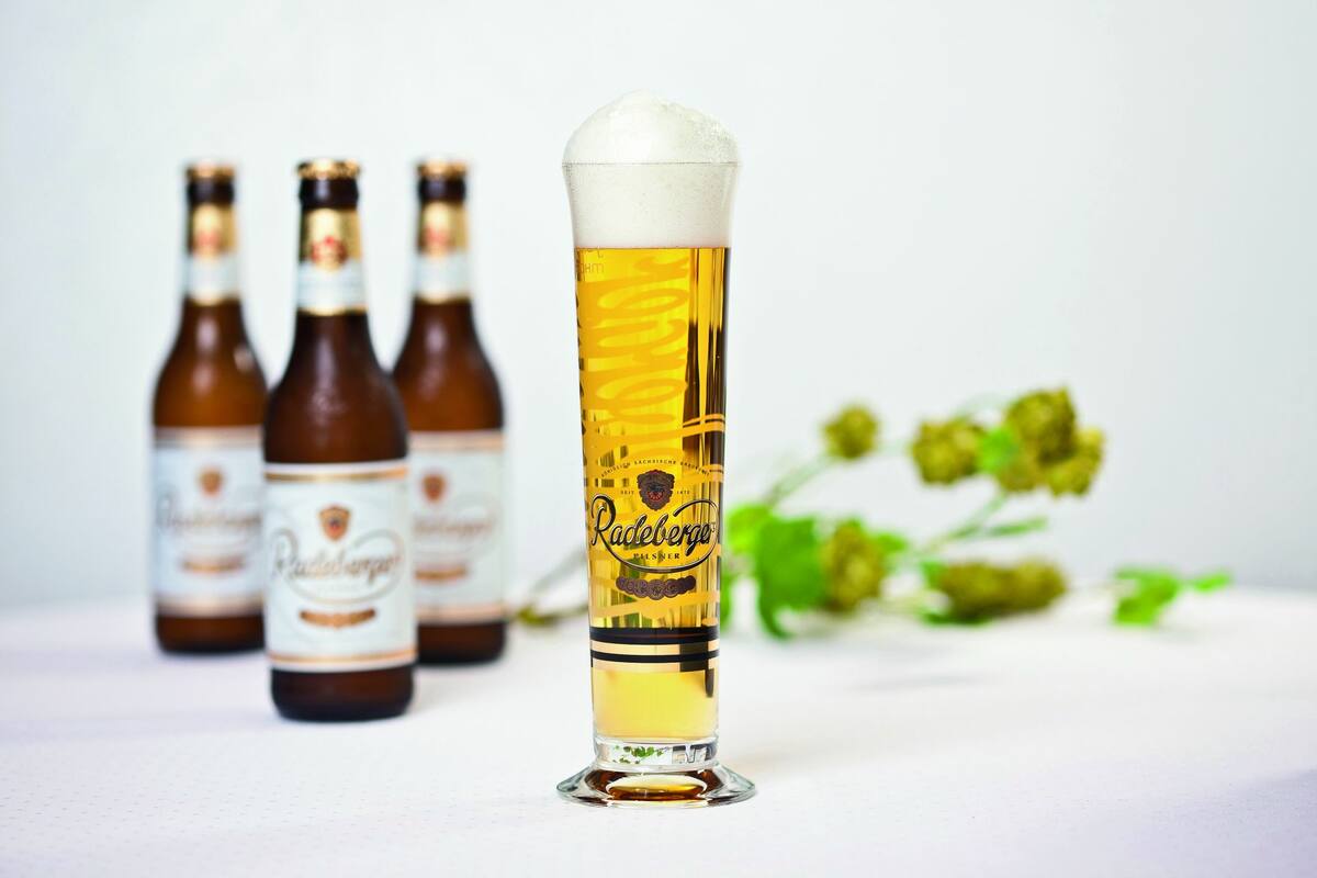 Foto von einem Glas Radeberger Pilsener und drei Flaschen Bier