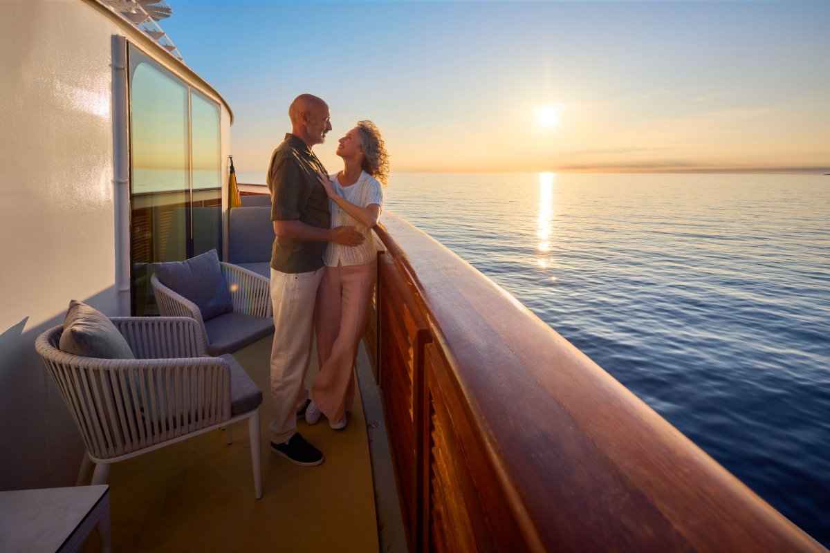 Paar auf Balkon einer Suite bei Sonnenuntergang 