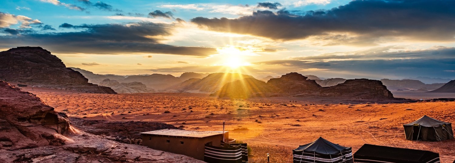 Sonne geht hinter Bergen in der Wüste unter