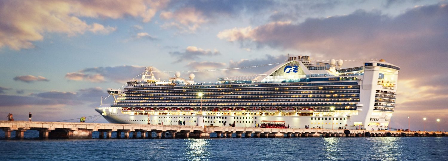 Die Caribbean Princess hell erleuchtet vor Anker in der Abenddämmerung