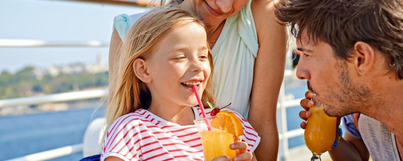 Eine Familie sitzt an der Reling und genießt leckeren Orangesaft