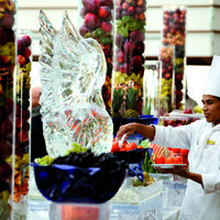 Ein Koch bereitet ein Buffet mit Früchten und Eisskulptur vor