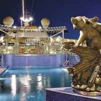 Blick über Pool und Pooldeck bei Nacht mit erleuchteten Statuen