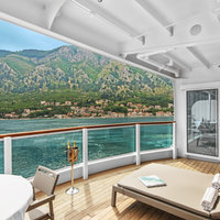 Bild Bilder: Seabourn Ovation Balkonkabine & Suite Wintergarten Suite mit Ausblick auf Meer und Küste, im Vordergrund Tisch, Stühle, Sonnenliege und Champagner